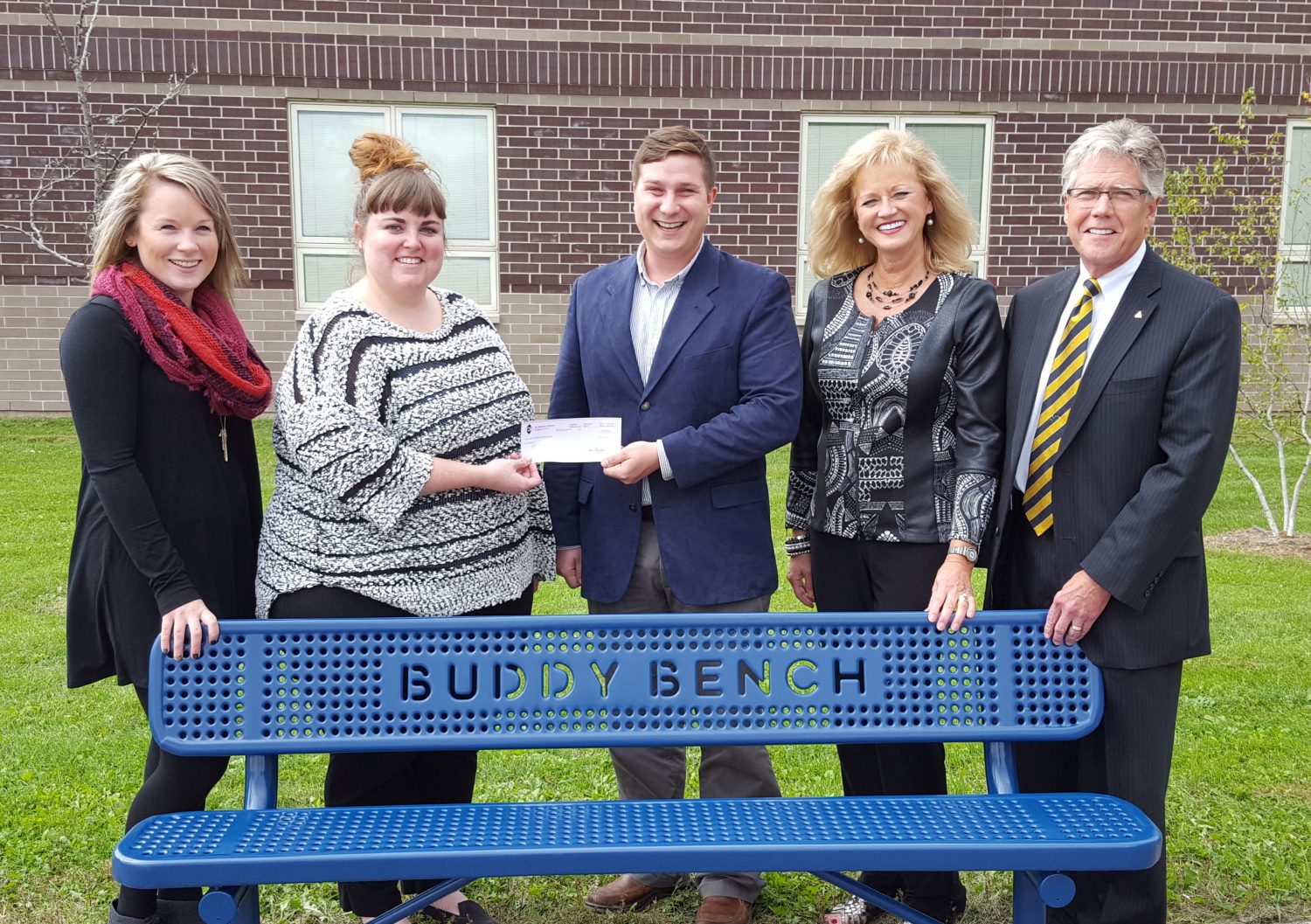 From left: Renee Binder, Miranda Gregory, Kyle Weik, Cindy Burns, and Dan Burns pose with an IMT Community Contest-winning Buddy Bench.
