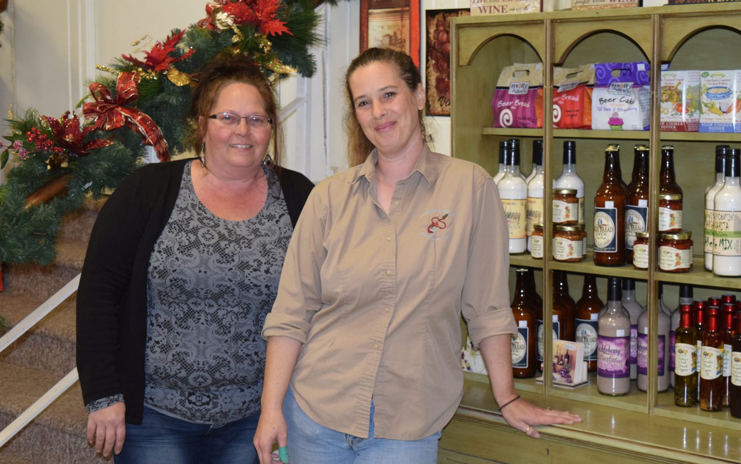 Illusions and Design manager Angie Young, left, and owner Sheri Dana stand by their expanded gourmet section at their new location.