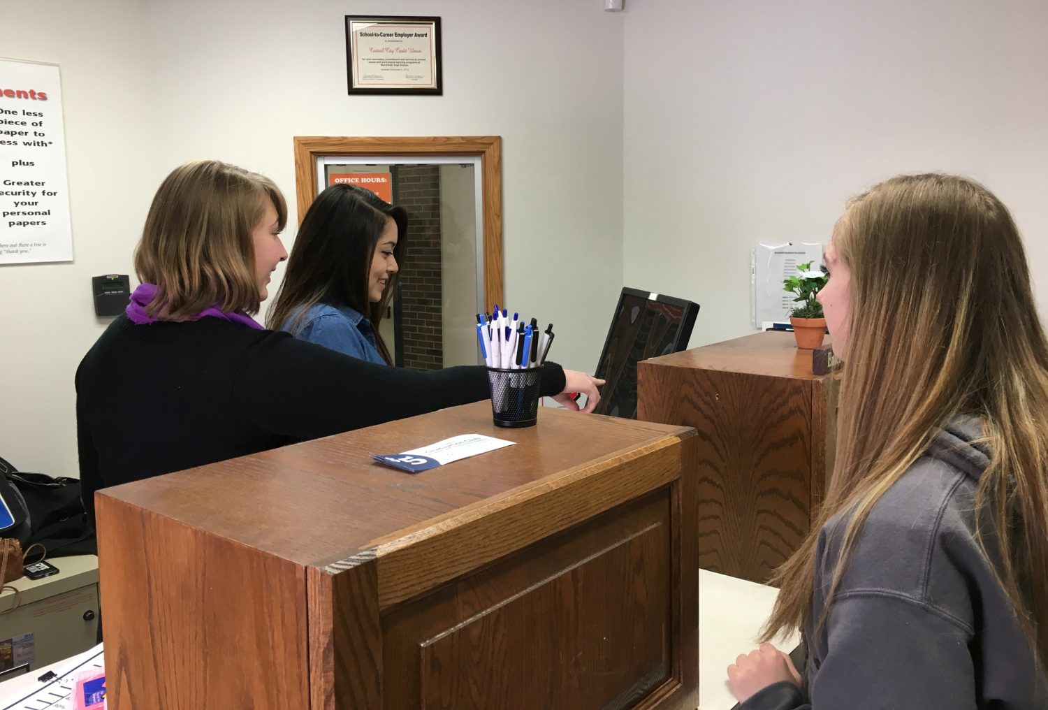 From right: Emily Cook, a senior at Marshfield High School, completes a transaction at Simplicity Credit Union's high school branch with Magaly Moreno and Ashley Landwehr.