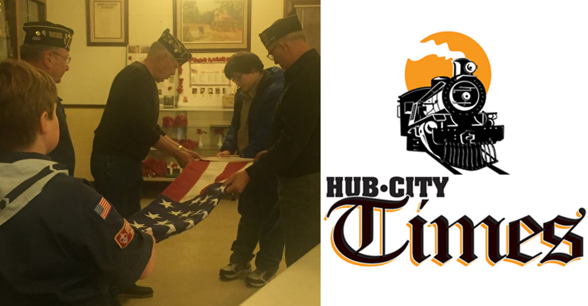 Members of the American Legion Post 54 Honor Guard offer guidance and encouragement to the scouts on folding the American flag.