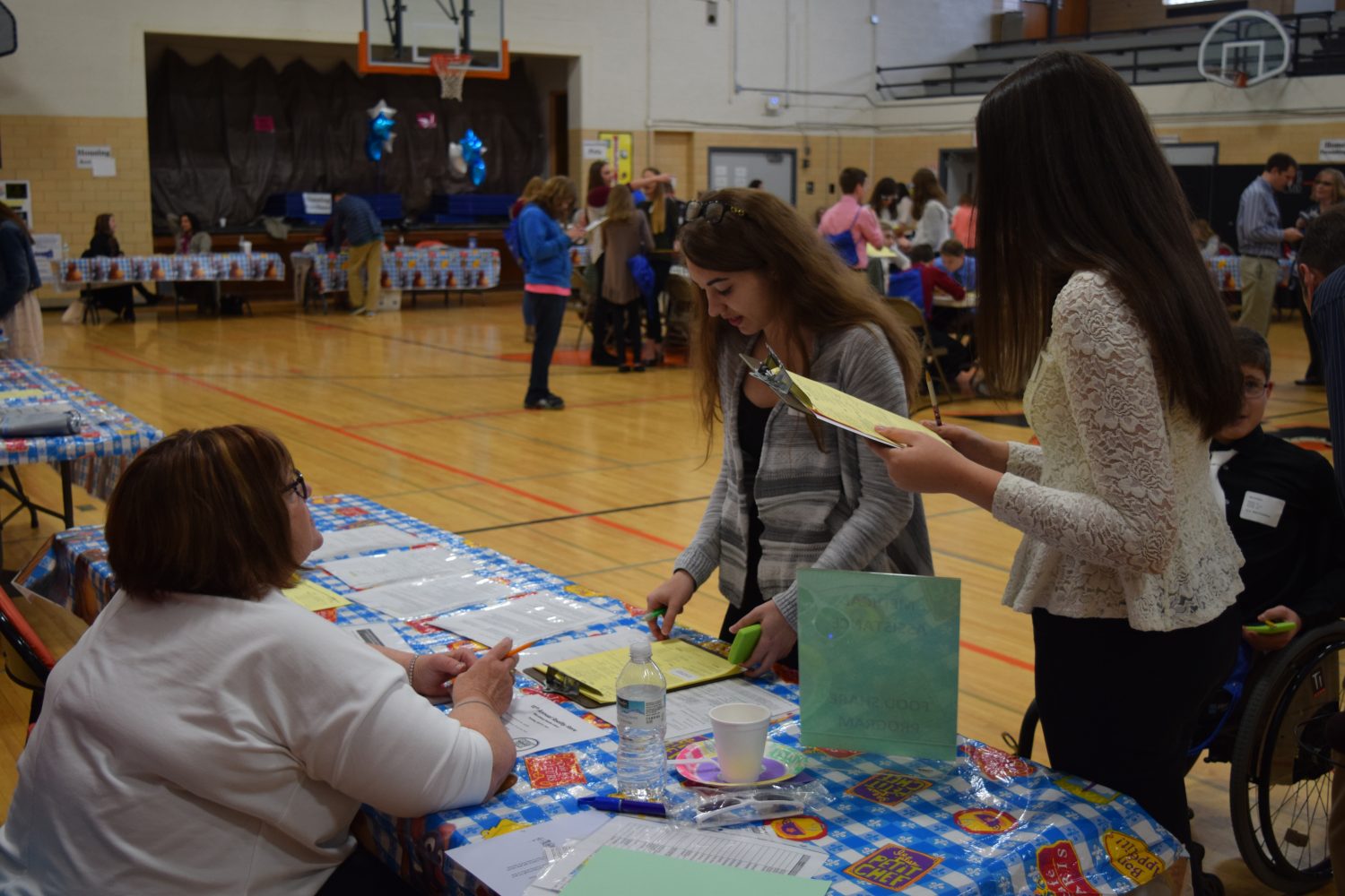 From left: Volunteer Patsy Baltus advises Marshfield Columbus Catholic students Sydney Litwaitis and Katja Krolo in the social services and job center section of the Reality Store held at Marshfield Middle School on April 11.